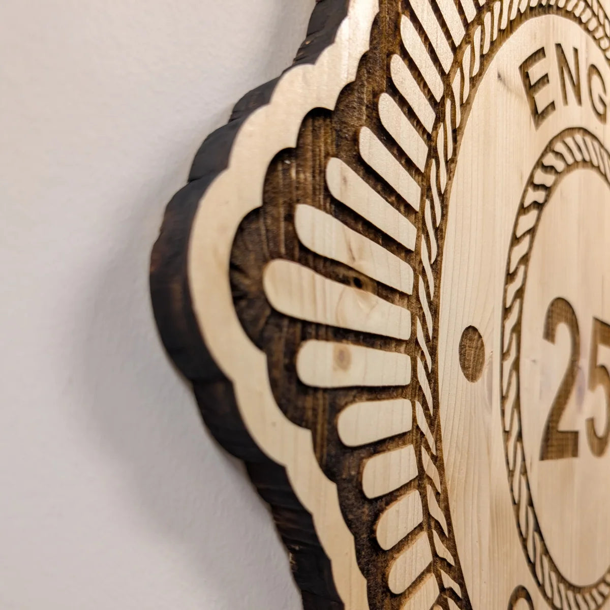 Close-up of detailed laser engraving and perimeter-cut edge on a wooden wall badge